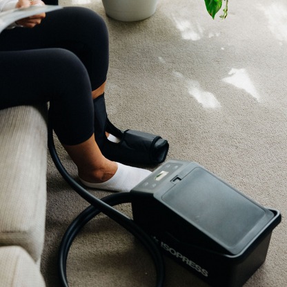 Woman sitting on couch using ankle cryocuff