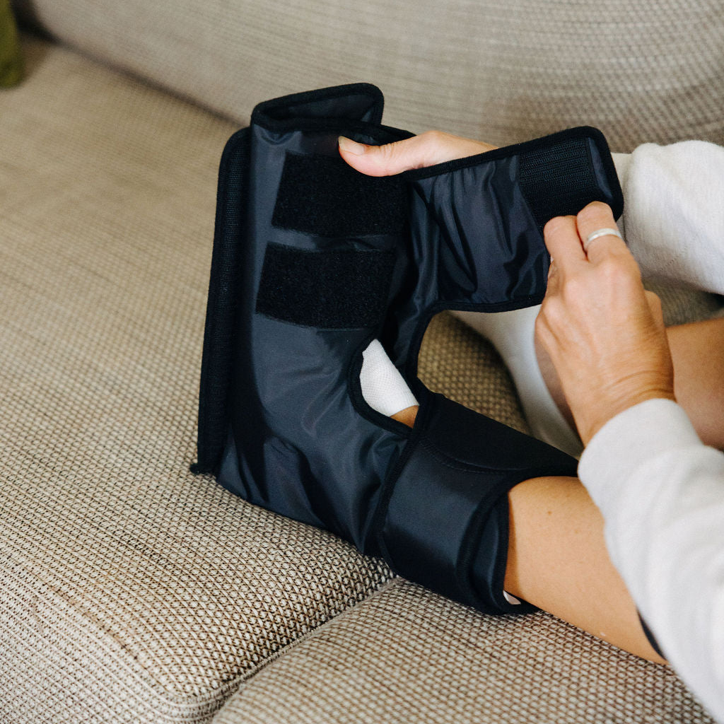 Woman sitting on a couch using a black compression device