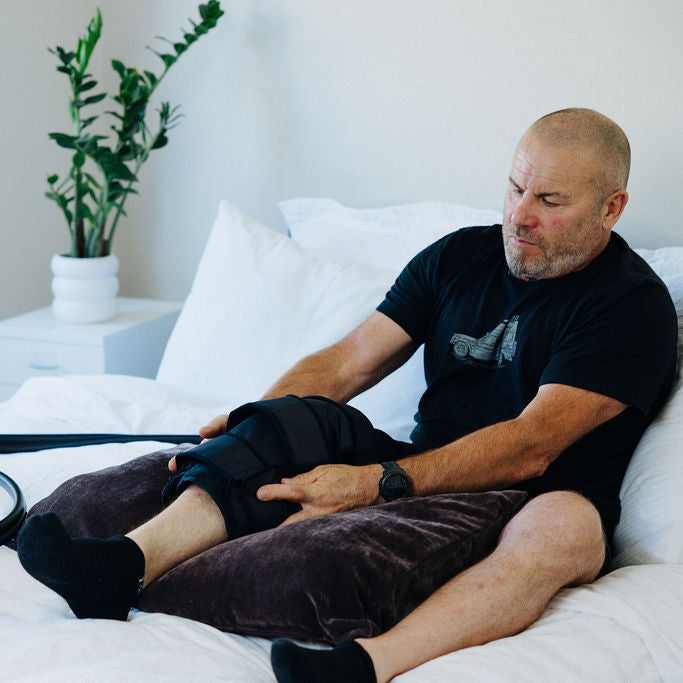 Man resting on bed wearing knee cuff