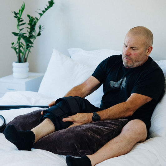 Man resting on bed wearing knee cuff