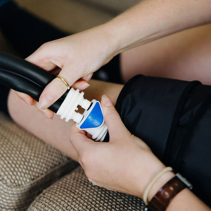 Person using an ISOPRESS leg cuff device on a couch