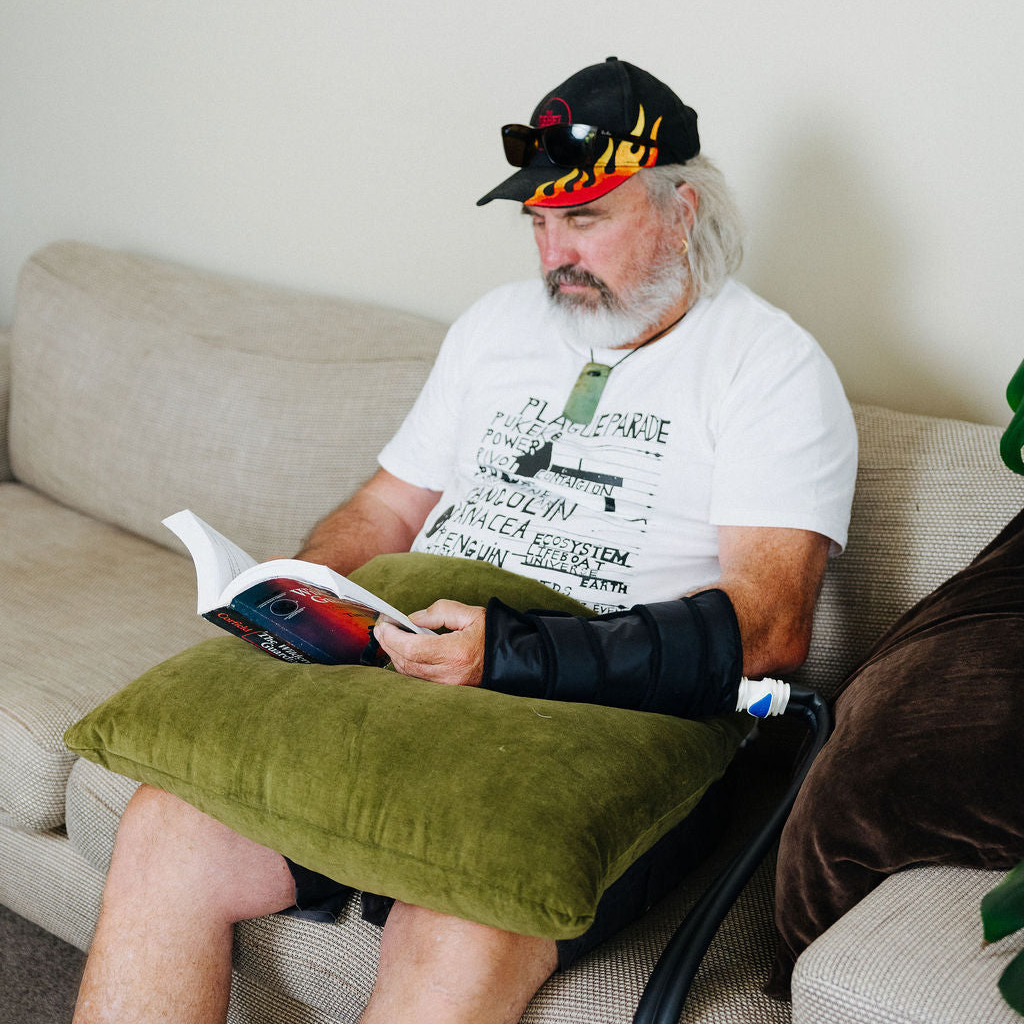 Person using an ice cryocuff on their wrist while sitting on a couch.