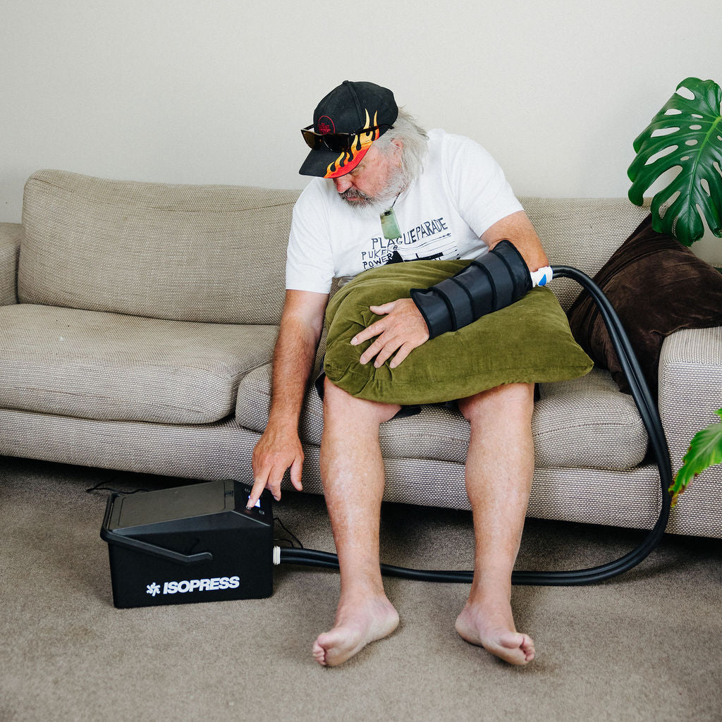 Person using an ice cryocuff on their wrist while sitting on a couch.