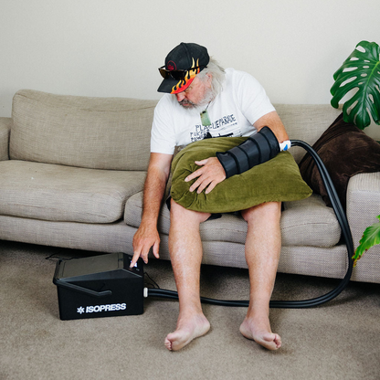 Person using an ice cryocuff on their wrist while sitting on a couch.
